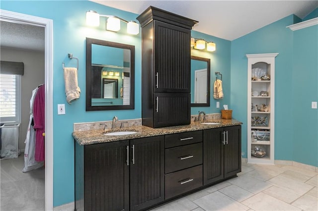 full bath with baseboards, double vanity, a sink, and vaulted ceiling