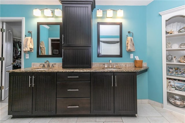 full bathroom with tile patterned floors, a walk in closet, double vanity, and a sink