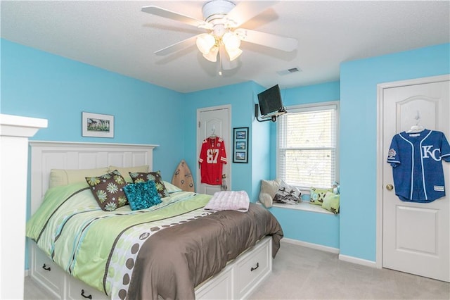 bedroom with visible vents, baseboards, a ceiling fan, and light carpet