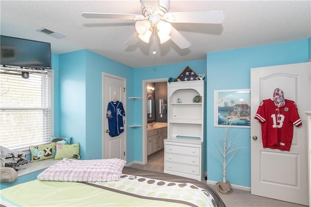 bedroom featuring ceiling fan, a textured ceiling, ensuite bath, visible vents, and baseboards