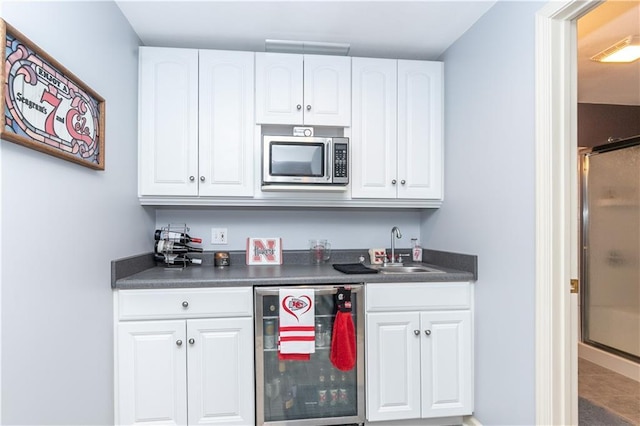 bar with a sink, stainless steel microwave, beverage cooler, and indoor wet bar