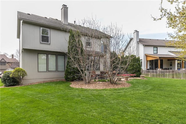 back of property featuring fence, a lawn, and a chimney