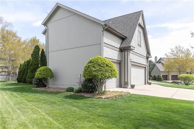 view of side of home featuring a yard, roof with shingles, an attached garage, and concrete driveway