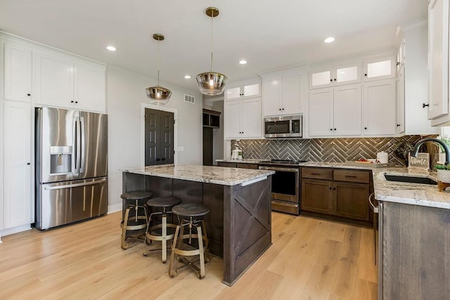 3141 SW Summit View Trl, Lees Summit, MO 64082 - kitchen featuring appliances with stainless steel finishes, a sink, white cabinets, decorative backsplash, and a kitchen island