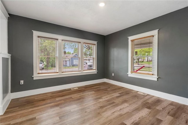 spare room featuring baseboards, visible vents, and wood finished floors