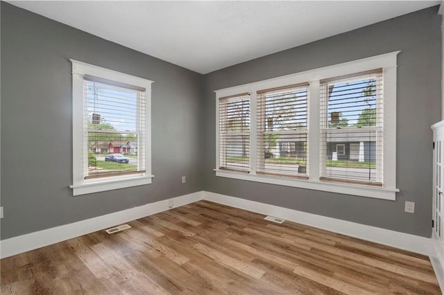 empty room with a healthy amount of sunlight, baseboards, and visible vents