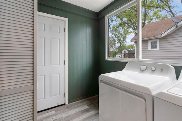 laundry area with independent washer and dryer, wooden walls, laundry area, and wood finished floors