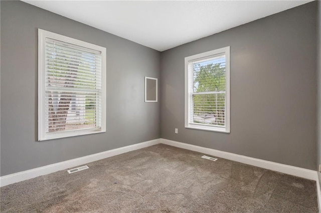 carpeted empty room featuring baseboards and visible vents
