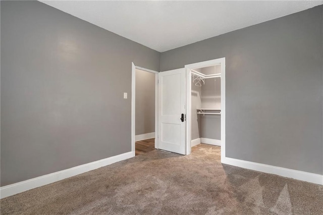 unfurnished bedroom with carpet flooring, baseboards, a spacious closet, and a closet
