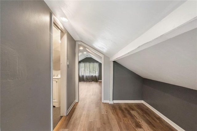 additional living space featuring baseboards, wood finished floors, and lofted ceiling
