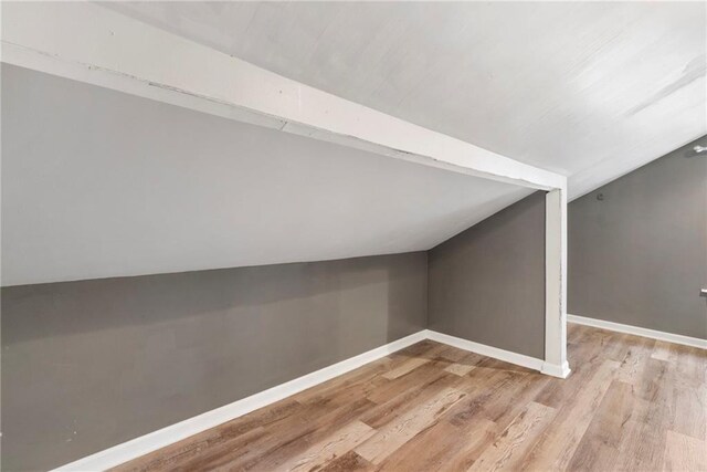 additional living space featuring baseboards, light wood-style flooring, and lofted ceiling