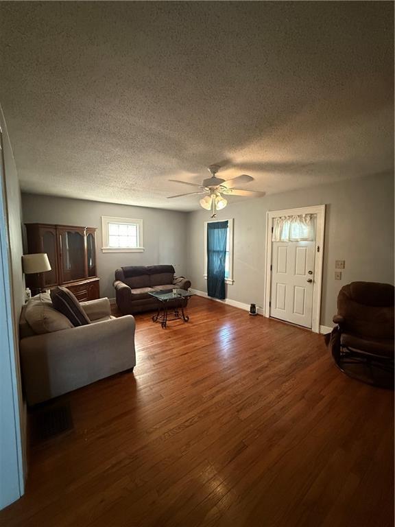 110 W Mechanic Ave, Independence, MO 64050 - living area featuring a textured ceiling, dark wood-style flooring, ceiling fan, and baseboards
