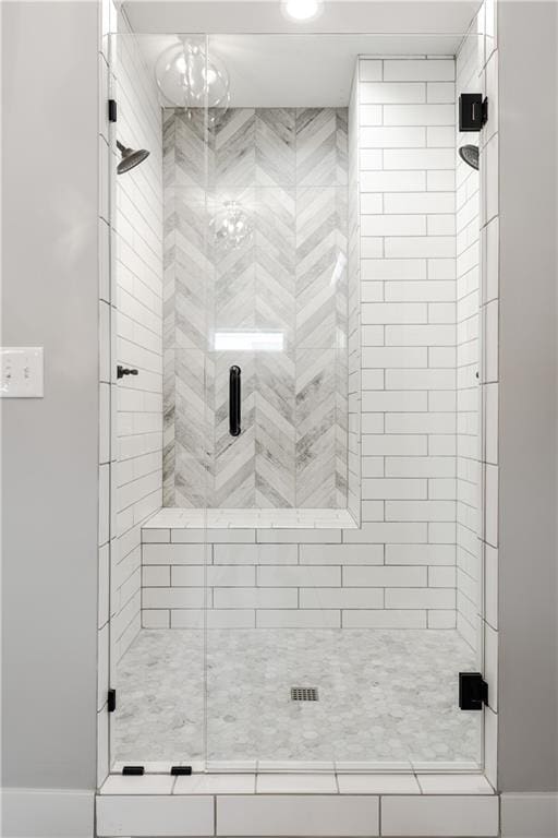 full bathroom with a shower stall and a notable chandelier