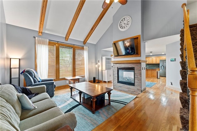 8110 NE 72nd Ter, Kansas City, MO 64158 - living area featuring a stone fireplace, beamed ceiling, ceiling fan, high vaulted ceiling, and light wood finished floors