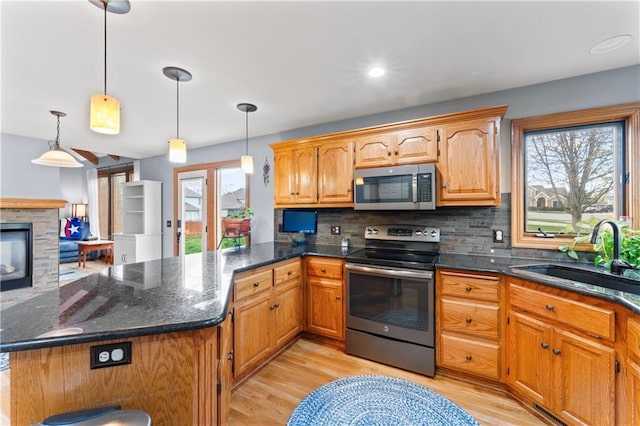 8110 NE 72nd Ter, Kansas City, MO 64158 - kitchen featuring a sink, a peninsula, light wood finished floors, stainless steel appliances, and backsplash