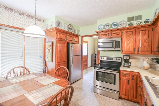 1601 S Market St, Holden, MO 64040 - kitchen featuring visible vents, light countertops, appliances with stainless steel finishes, a textured ceiling, and pendant lighting
