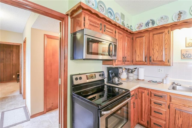 1601 S Market St, Holden, MO 64040 - kitchen with a sink, light countertops, appliances with stainless steel finishes, a textured ceiling, and brown cabinets