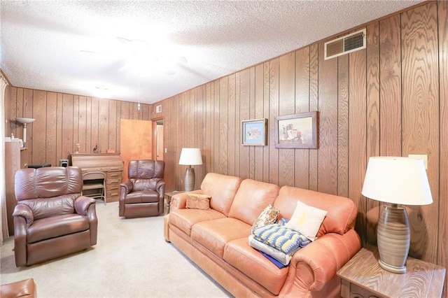 1601 S Market St, Holden, MO 64040 - living area featuring wooden walls, a textured ceiling, carpet floors, visible vents, and ceiling fan