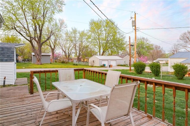 1601 S Market St, Holden, MO 64040 - wooden deck featuring a yard, a detached garage, outdoor dining space, an outdoor structure, and a residential view