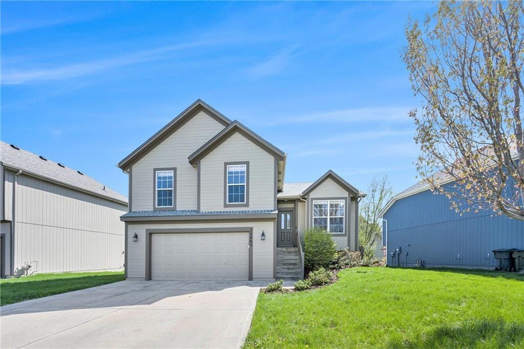 tri-level home with a front yard, driveway, and an attached garage