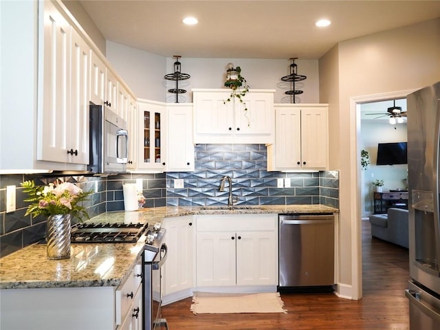 kitchen with stainless steel appliances, a sink, dark wood finished floors, glass insert cabinets, and ceiling fan