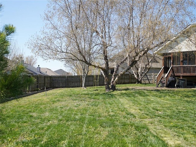 view of yard with a fenced backyard, a sunroom, a deck, and stairs
