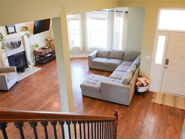 living area with baseboards, wood finished floors, and a fireplace with raised hearth