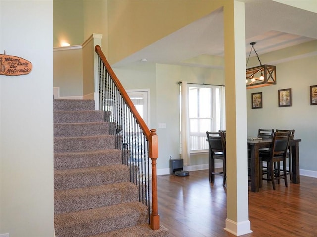stairs with baseboards, a chandelier, and wood finished floors