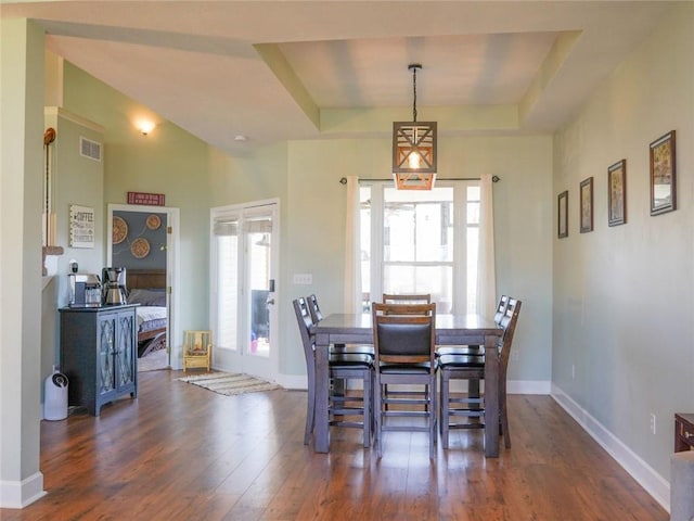 dining room with visible vents, baseboards, a raised ceiling, and dark wood-style flooring