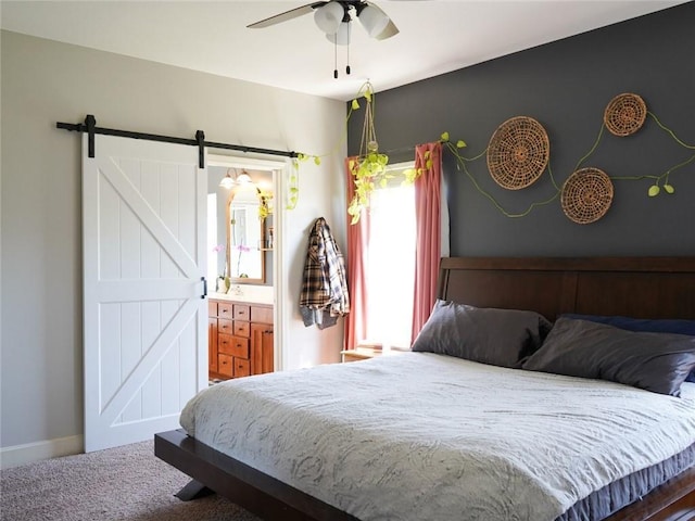 carpeted bedroom featuring baseboards, connected bathroom, and a barn door