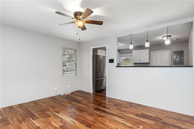 unfurnished living room featuring electric panel, a ceiling fan, and dark wood finished floors