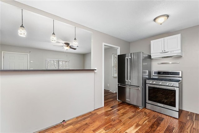 kitchen with a ceiling fan, white cabinets, appliances with stainless steel finishes, wood finished floors, and under cabinet range hood