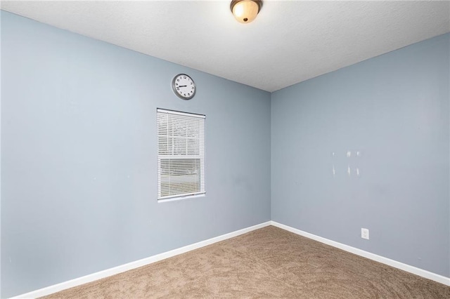 carpeted empty room featuring baseboards
