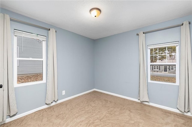 carpeted spare room featuring a textured ceiling and baseboards