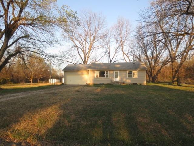 ranch-style house featuring a front yard, dirt driveway, and a garage