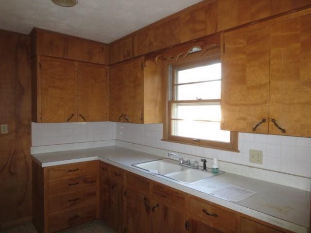 kitchen featuring a sink, brown cabinetry, light countertops, and tasteful backsplash
