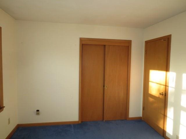 unfurnished bedroom with carpet floors, baseboards, and a closet