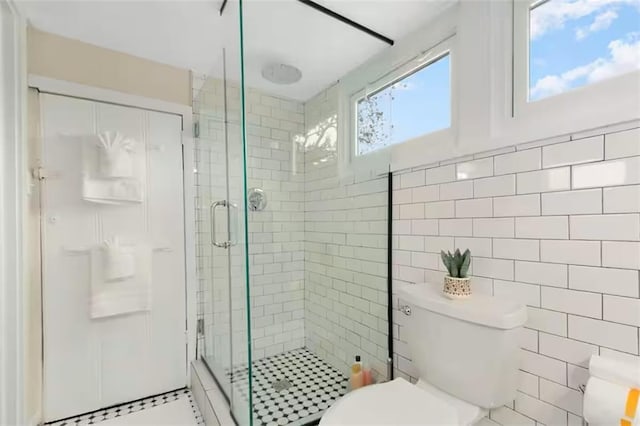 full bathroom with a stall shower, tile walls, and toilet