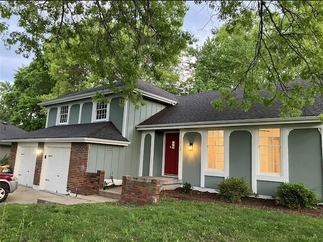 tri-level home with board and batten siding, concrete driveway, a shingled roof, and a front yard