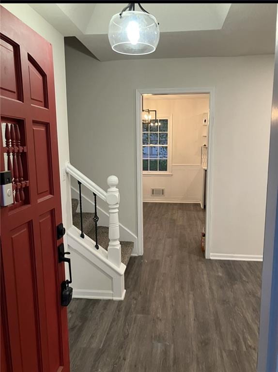 entrance foyer with visible vents, dark wood-style flooring, baseboards, and an inviting chandelier