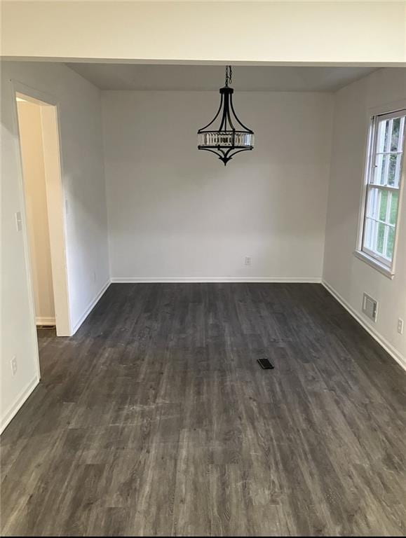 unfurnished dining area featuring baseboards, dark wood finished floors, and visible vents