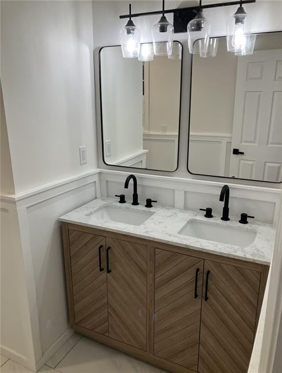 bathroom with double vanity, a sink, and a decorative wall