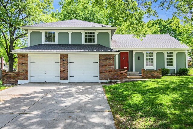 11715 E 60th St, Kansas City, MO 64133 - split level home featuring an attached garage, stucco siding, concrete driveway, a porch, and a front lawn