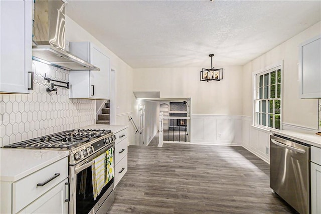 11715 E 60th St, Kansas City, MO 64133 - kitchen featuring light countertops, dark wood-type flooring, wall chimney range hood, appliances with stainless steel finishes, and tasteful backsplash