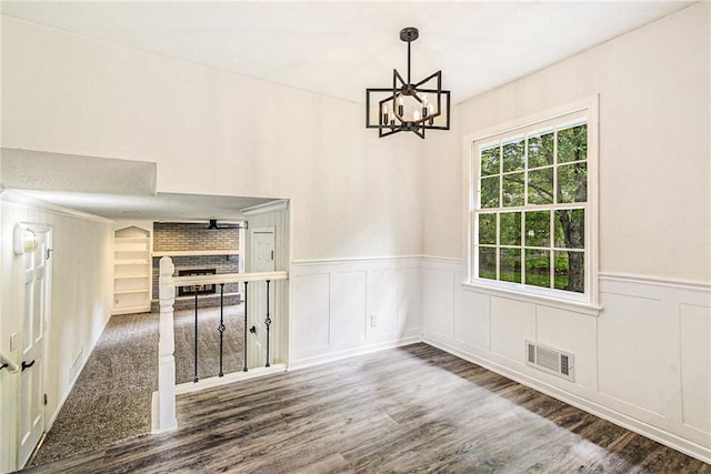 11715 E 60th St, Kansas City, MO 64133 - unfurnished dining area with a decorative wall, wood finished floors, visible vents, a brick fireplace, and wainscoting