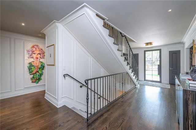 stairway featuring ornamental molding, wood finished floors, and a decorative wall