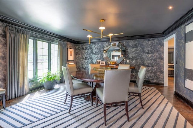 dining area with ornamental molding, wood finished floors, and wallpapered walls