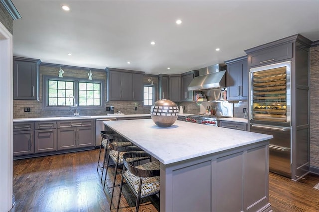 kitchen featuring wall chimney range hood, stainless steel dishwasher, backsplash, and a sink