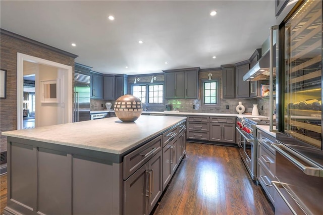 kitchen featuring backsplash, a kitchen island, high quality appliances, dark wood finished floors, and gray cabinetry