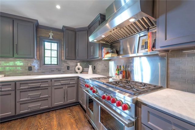 kitchen with light countertops, ventilation hood, range with two ovens, backsplash, and gray cabinetry